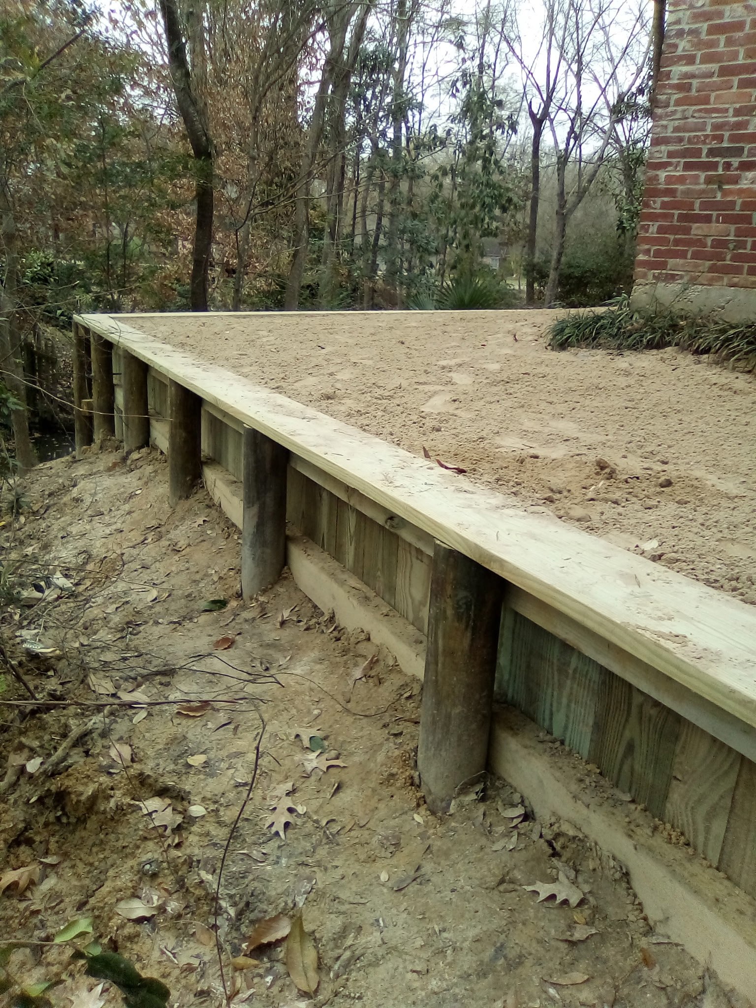 Timber retaining wall for erosion control, Baton Rouge Long timber retaining wall controlling erosion along the side of a Baton Rouge home