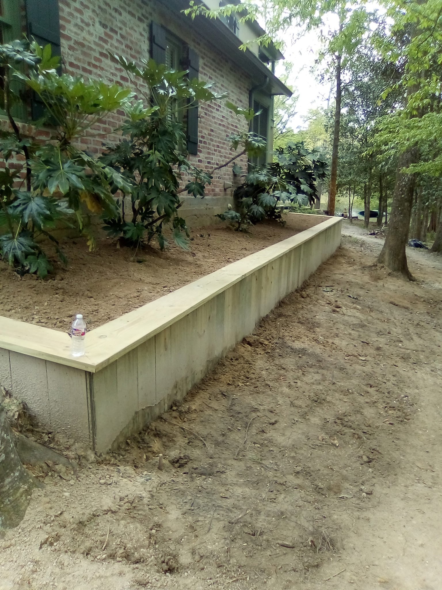 Treated timber retaining wall and grade leveling, Louisiana Treated timber retaining wall leveling a planting bed along the side of a Louisiana home