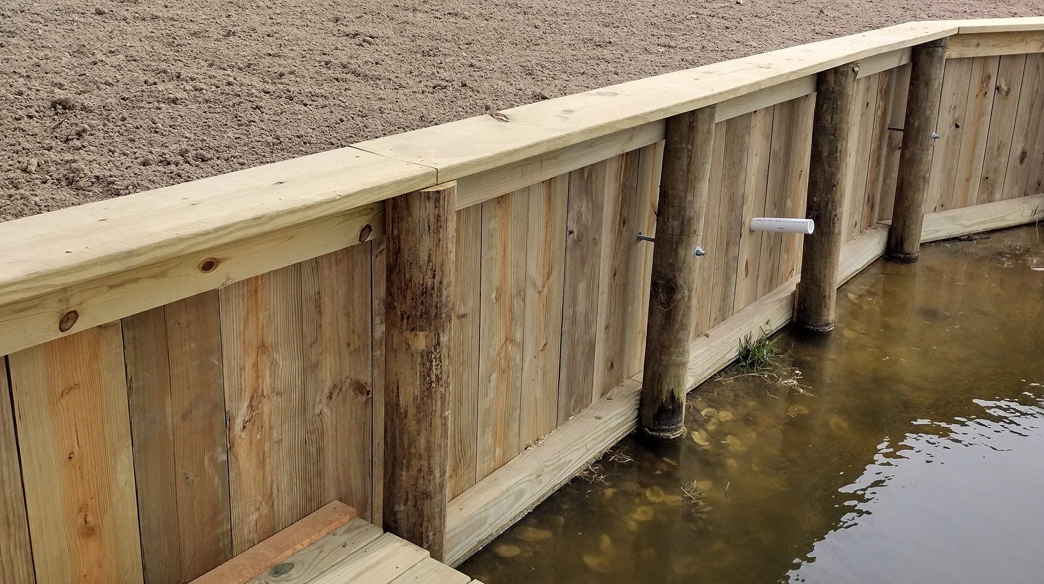 Timber bulkhead sea wall built by LA Fence & Bulkheads Newly built treated timber bulkhead sea wall holding a graded shoreline on a South Louisiana waterway